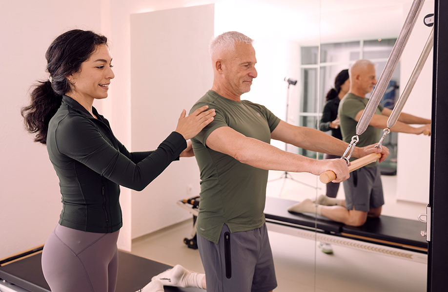 Founder of Intuitive Pilates Joana showing a client how to use the reformer. 